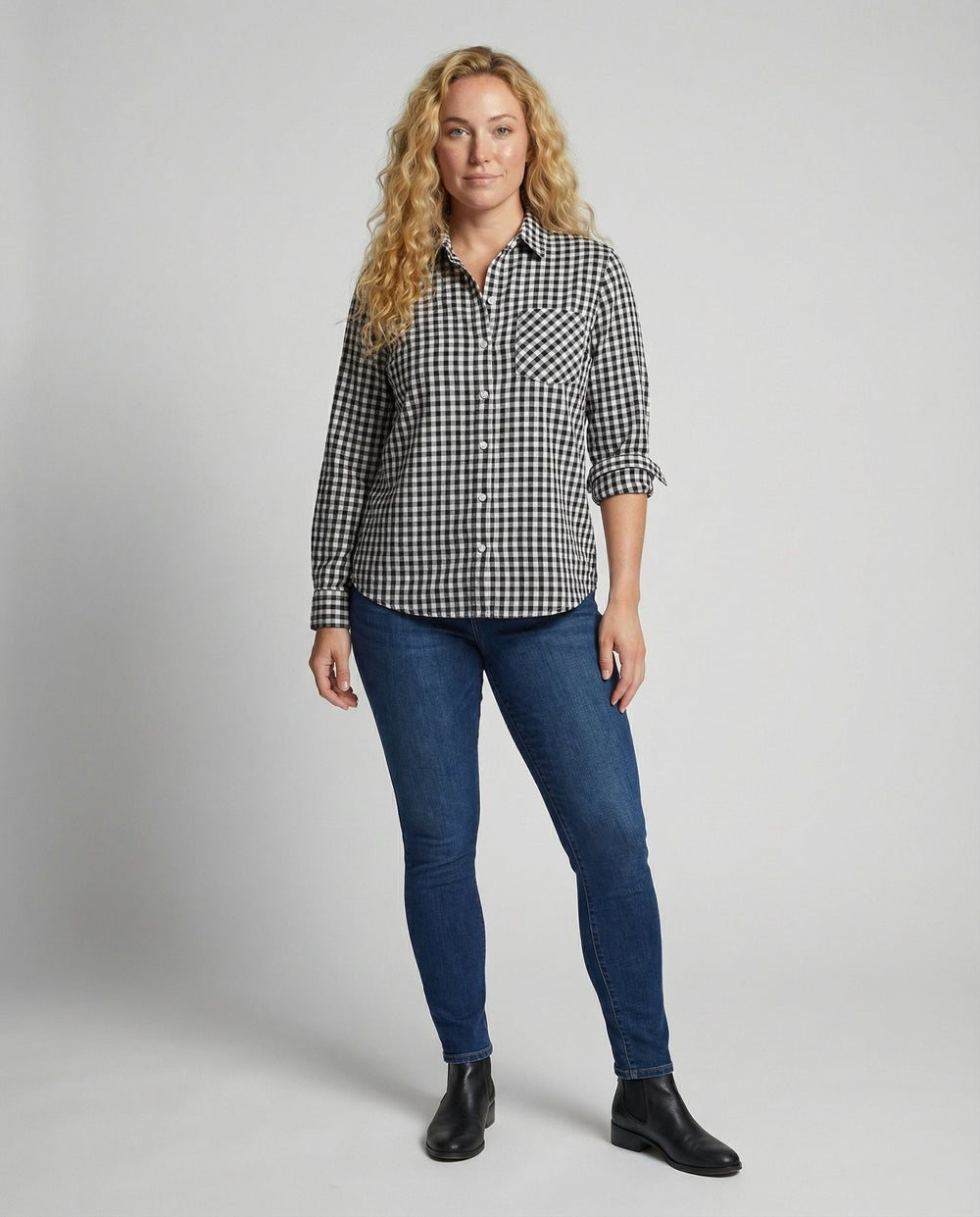 Woman in a relaxed plaid button-up shirt styled on a plain background.