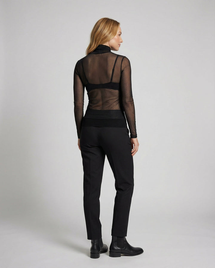 Female model showcasing a transparent long sleeve blouse with a high neckline.
