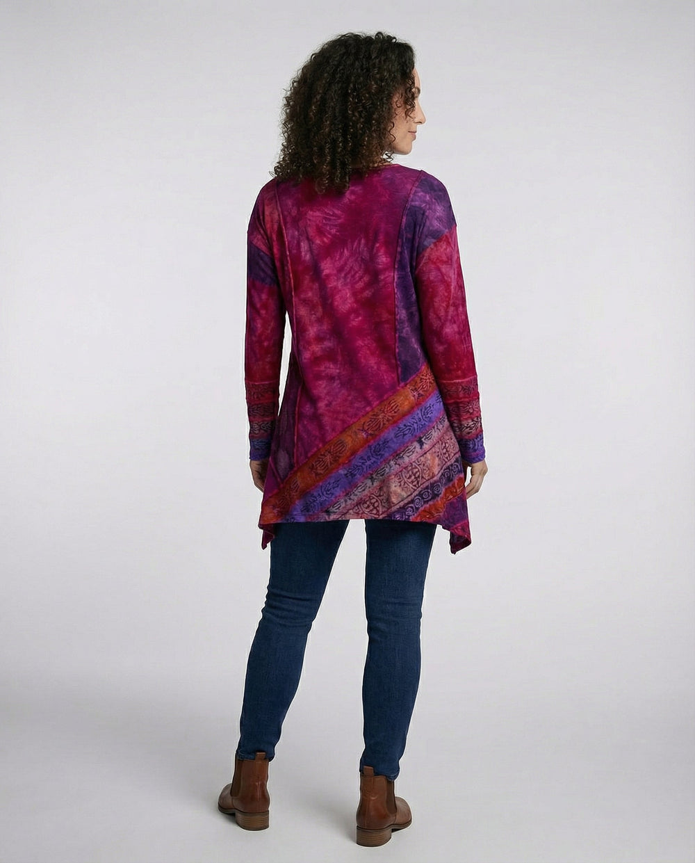 Woman in a vibrant printed tunic with long sleeves and a relaxed fit on a plain background.