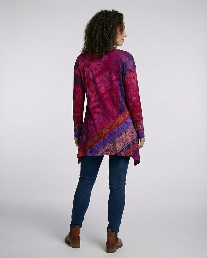 Woman in a vibrant printed tunic with long sleeves and a relaxed fit on a plain background.