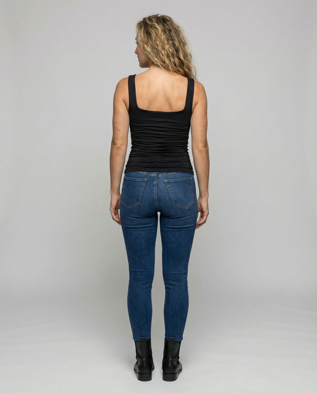 Woman wearing a soft stretch top with wide shoulder straps against a plain backdrop.
