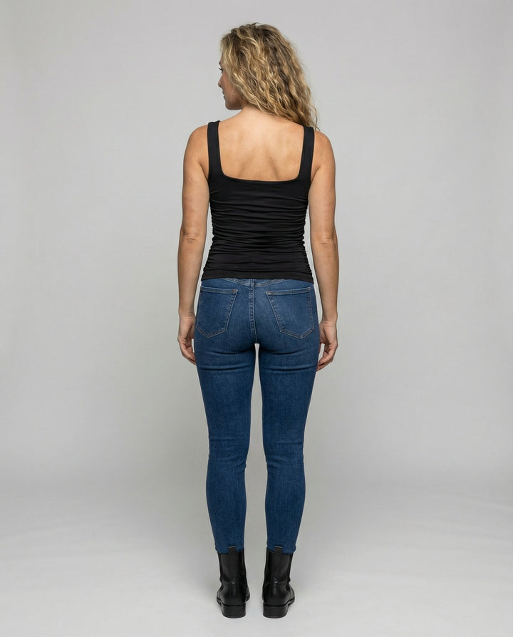 Woman wearing a soft stretch top with wide shoulder straps against a plain backdrop.
