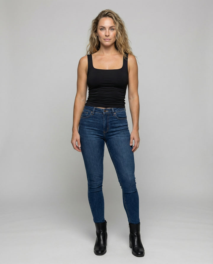 Woman in a sleeveless fitted top featuring a square neckline on a plain background.