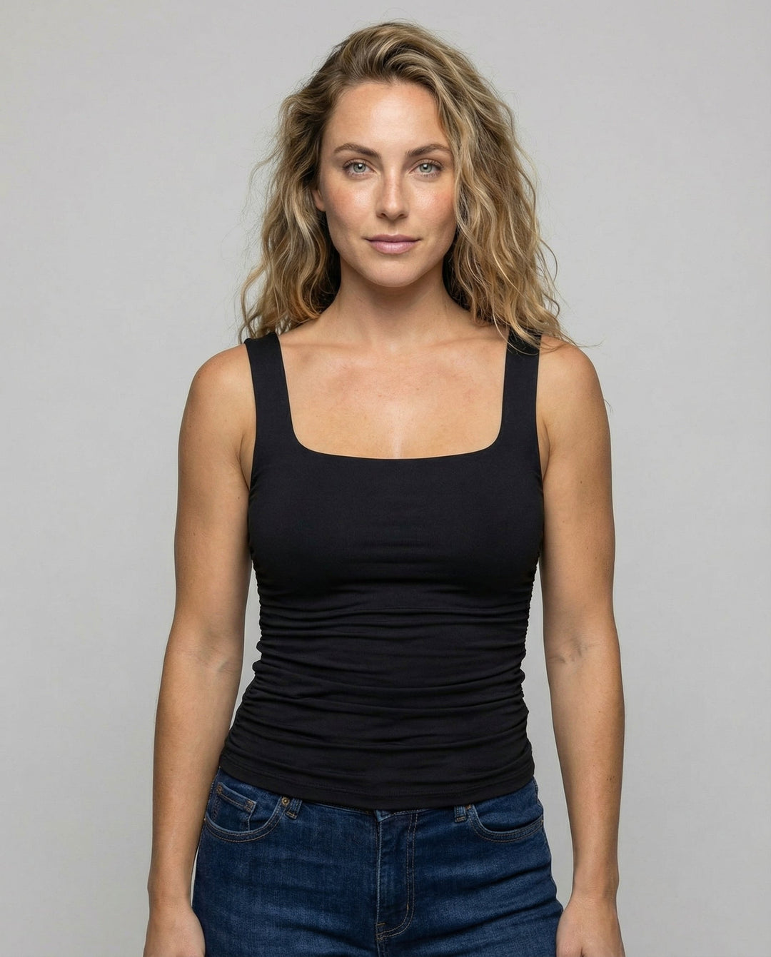 Female model wearing a fitted square neck top with wide straps against a plain background.