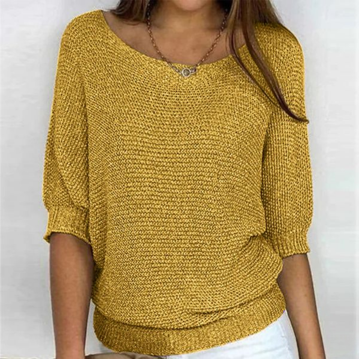 Female model wearing chic knit top slight angle plain background