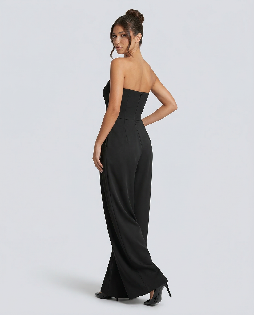 Woman in a minimal sleeveless jumpsuit against a plain background.