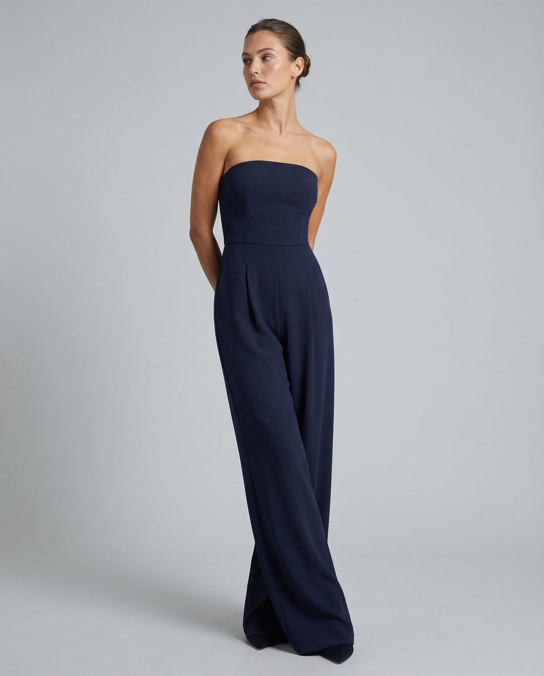 Woman in a structured bodice jumpsuit with relaxed trousers on a plain background.