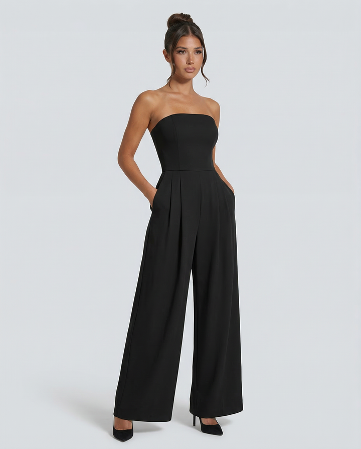 Female model wearing a structured strapless jumpsuit on a plain background.