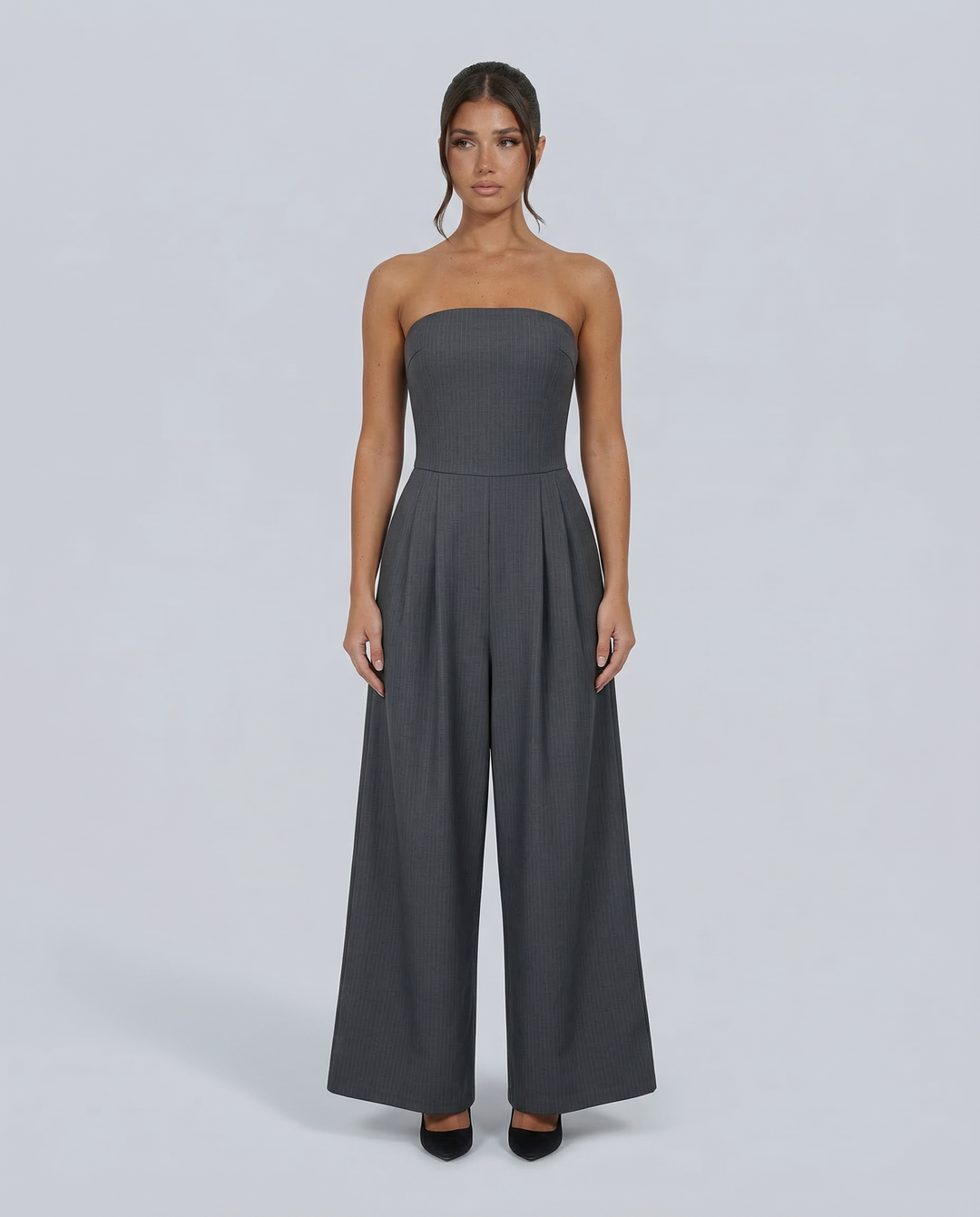 Woman wearing a fitted bodice jumpsuit with wide legs on a plain background.