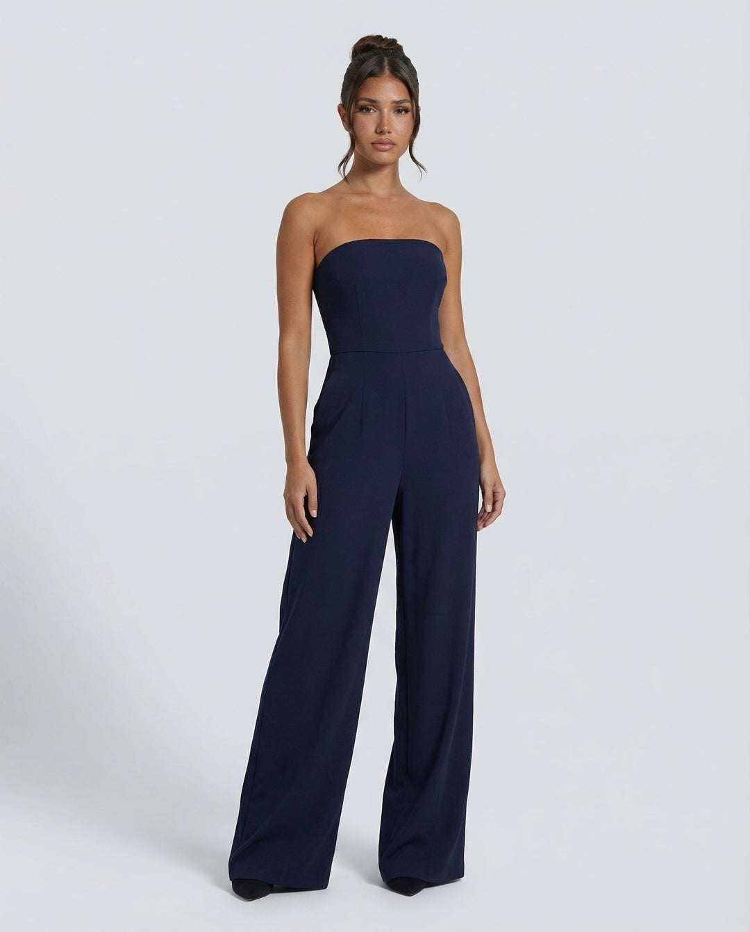 Woman wearing a strapless wide-leg jumpsuit on a plain background.