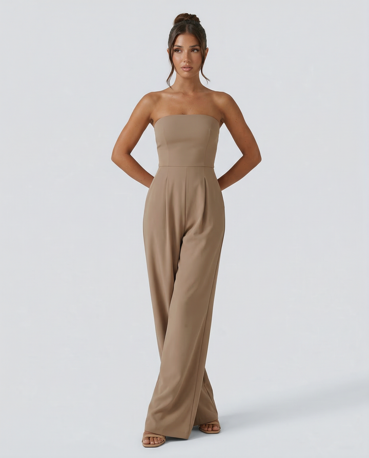 Female model wearing a navy strapless jumpsuit on a plain background.
