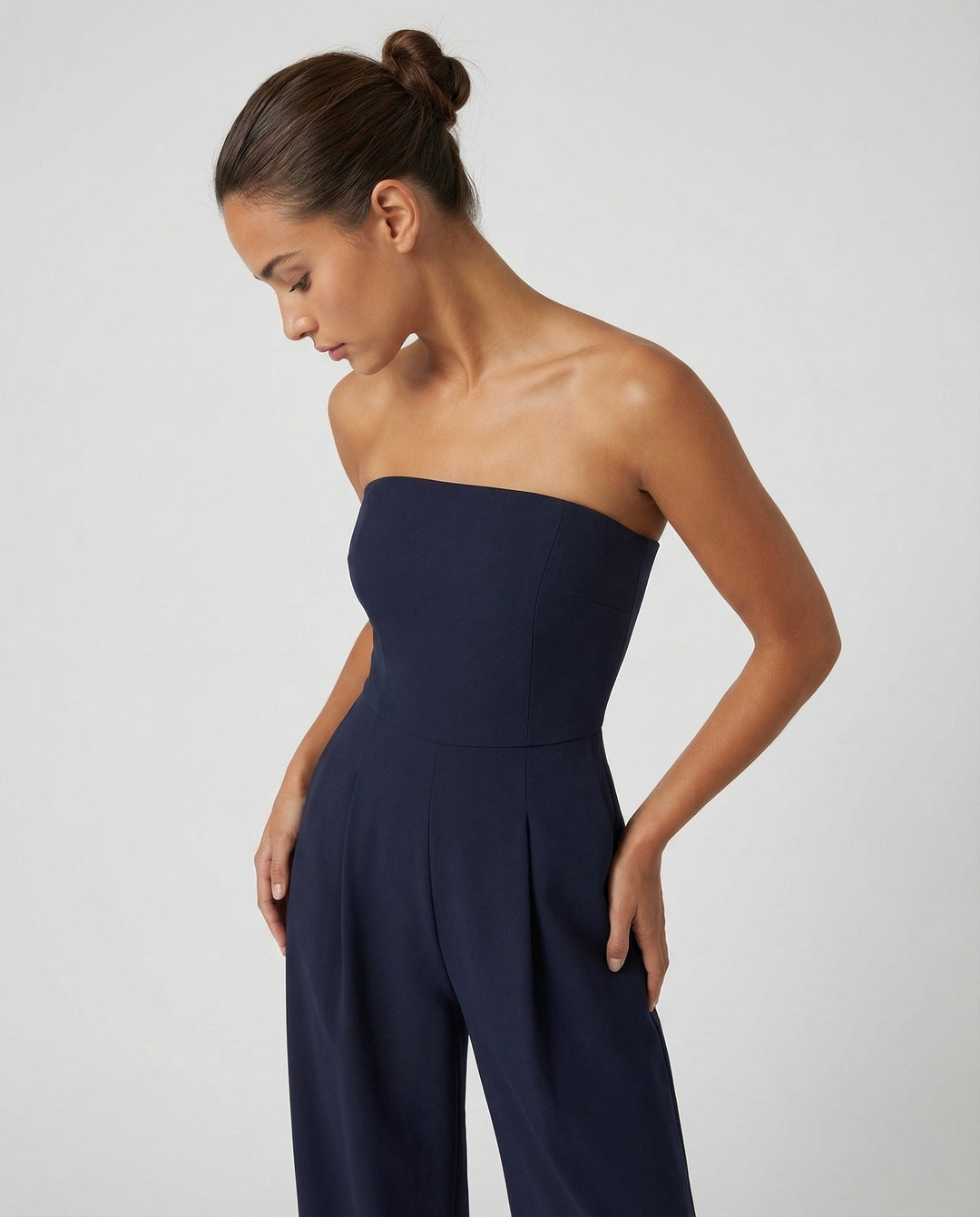 Woman styled in a wide-leg evening jumpsuit against a plain background.