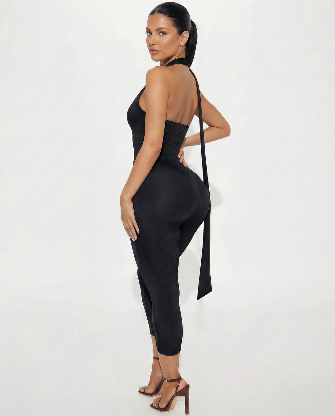 Female model showing a cropped leg evening outfit with high neck tie on a plain background.