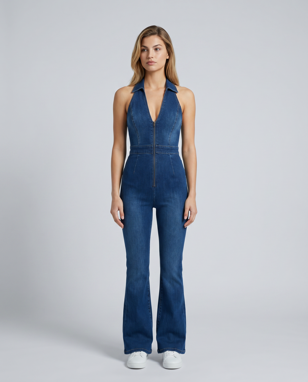 Female model wearing a blue flare leg denim jumpsuit on a plain background.