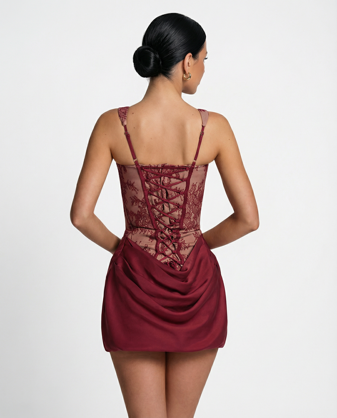 Model wearing a lace corset mini dress with lace-up back against a plain background.
