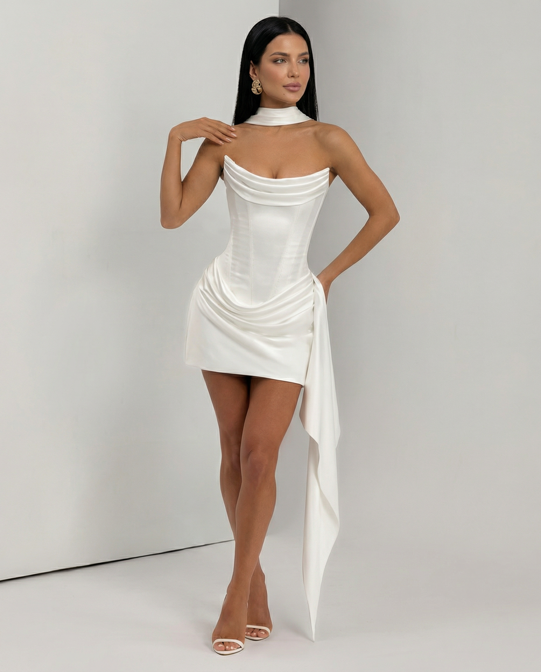 Woman wearing a strapless party mini dress with gathered skirt detail on a plain background.