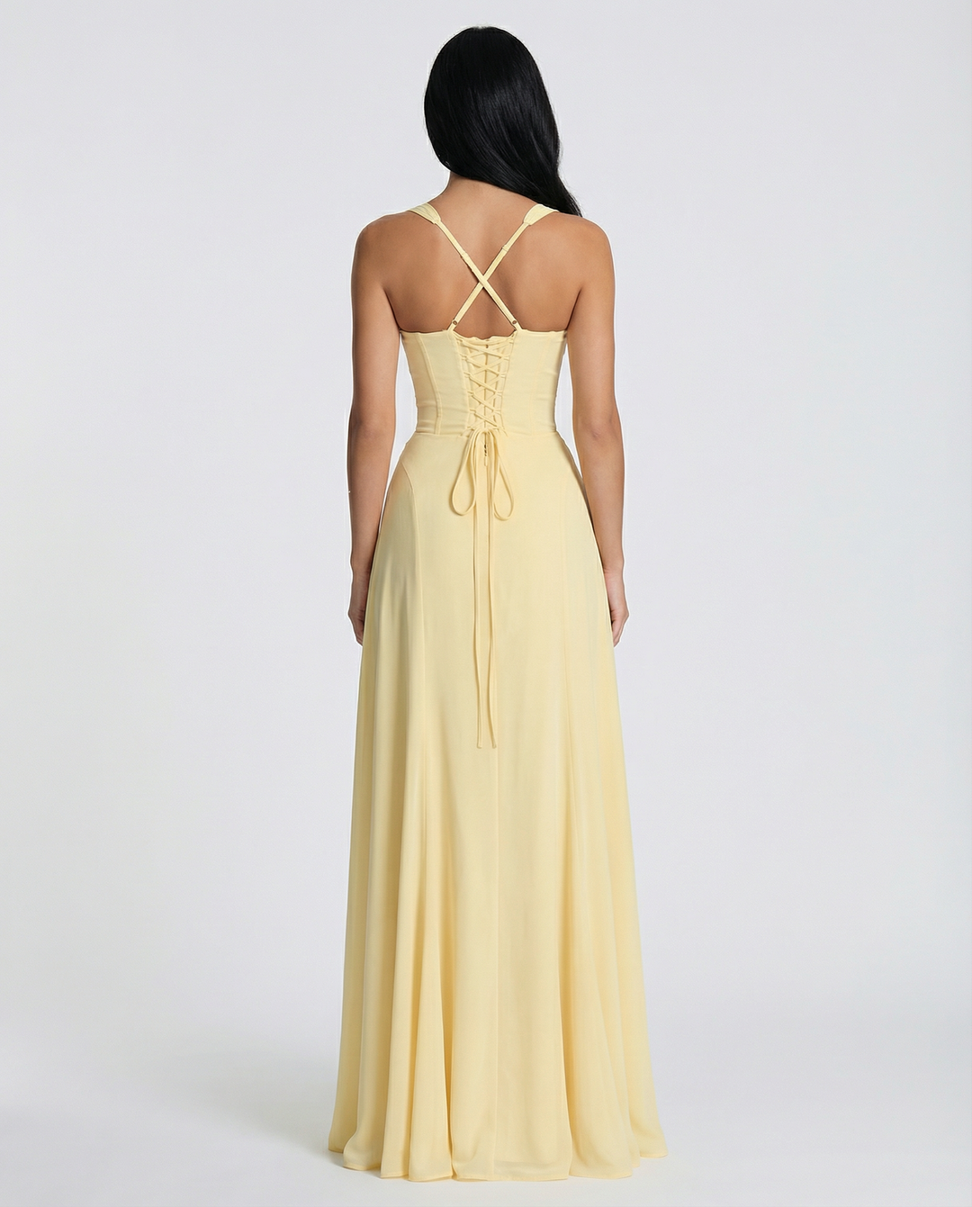 Female model wearing a yellow maxi dress with slim shoulder straps and a flowing silhouette.