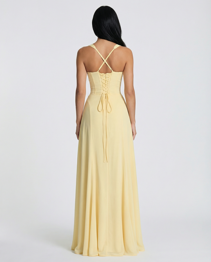 Female model wearing a yellow maxi dress with slim shoulder straps and a flowing silhouette.