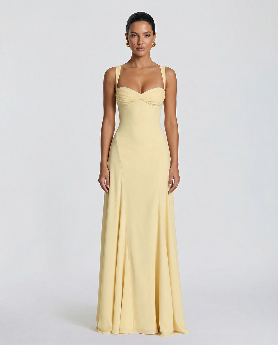 Woman in a yellow full-length dress featuring a fitted bodice and softly flared skirt on a plain background.