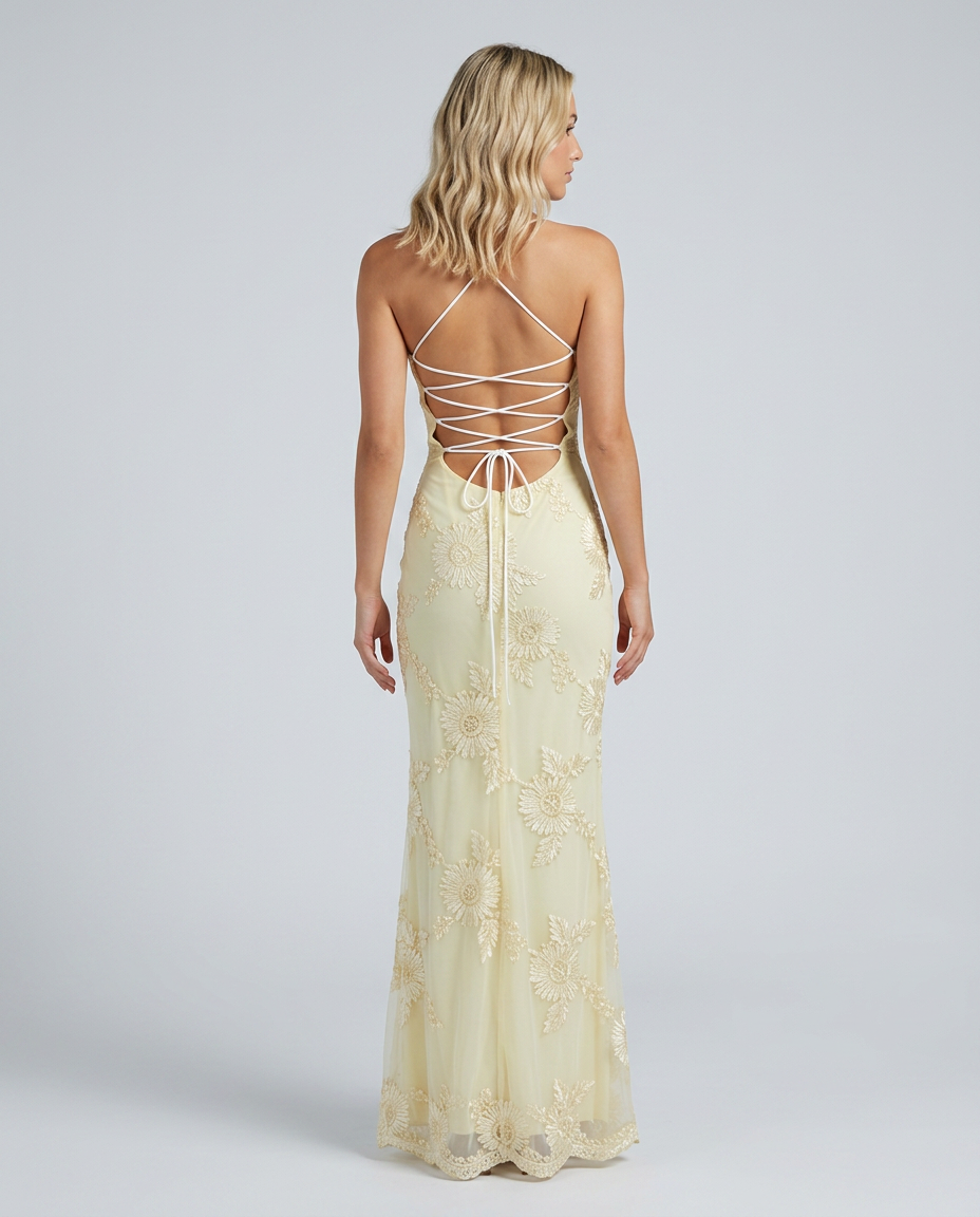 Woman in a fitted maxi dress featuring floral detailing and a lace-up back on a plain background.