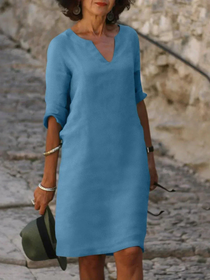 Woman wearing blue dress shown from front outdoors