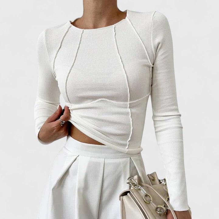 Female model wearing a tailored women’s top against a plain background.
