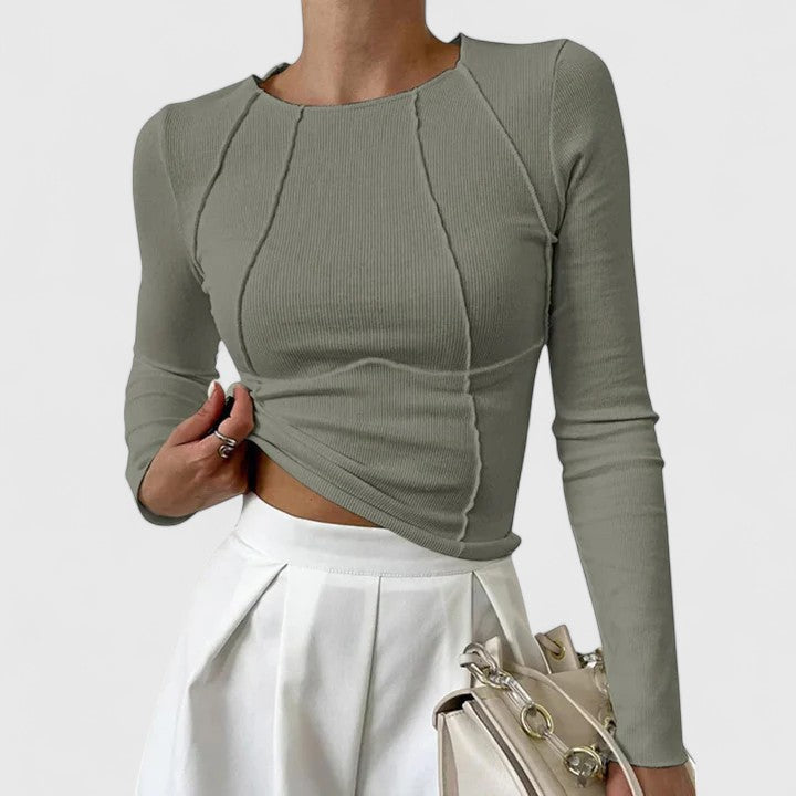 Woman in a soft fabric top standing against a clean background.