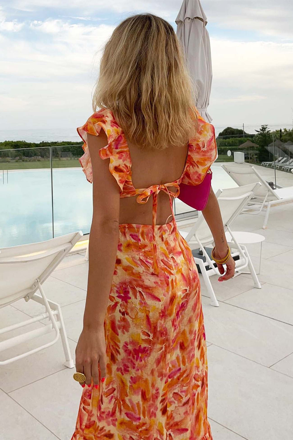 Model back angle showcasing long floral dress ruffle detail plain background