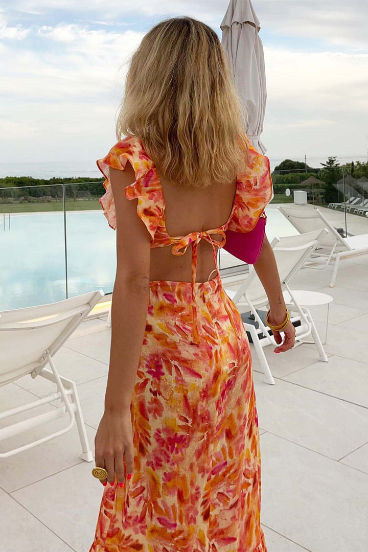 Model back angle showcasing long floral dress ruffle detail plain background