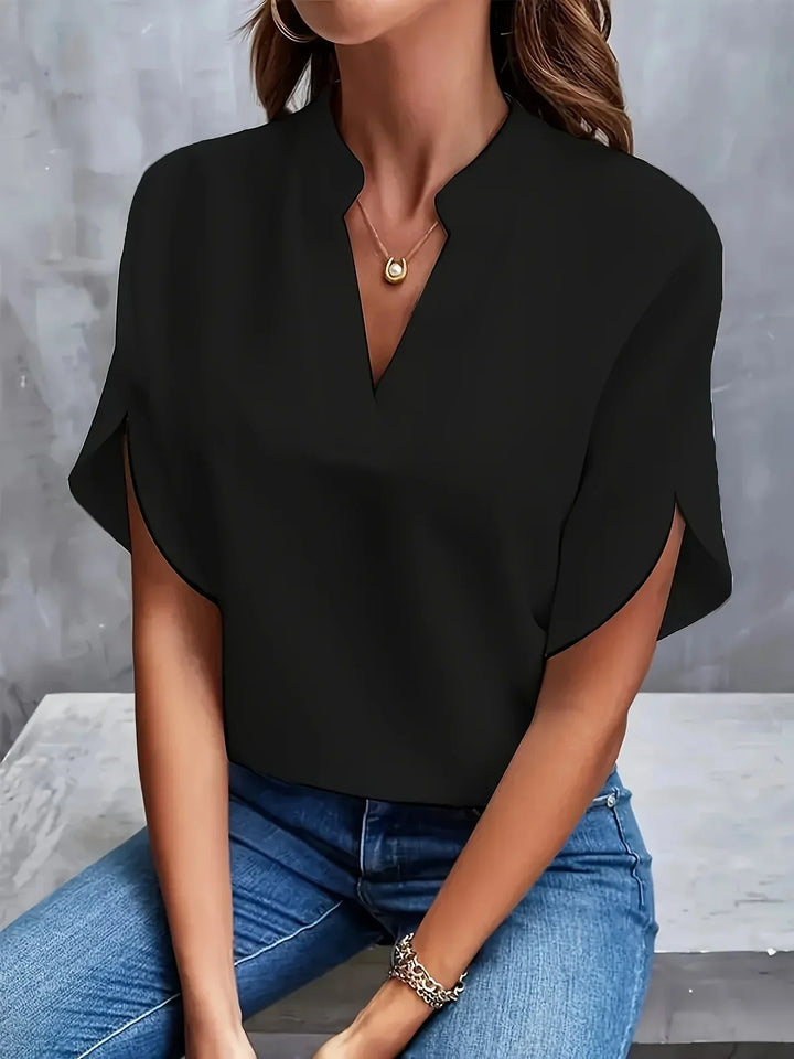 Female model in a polished V neck blouse styled for warm weather on a clean background.