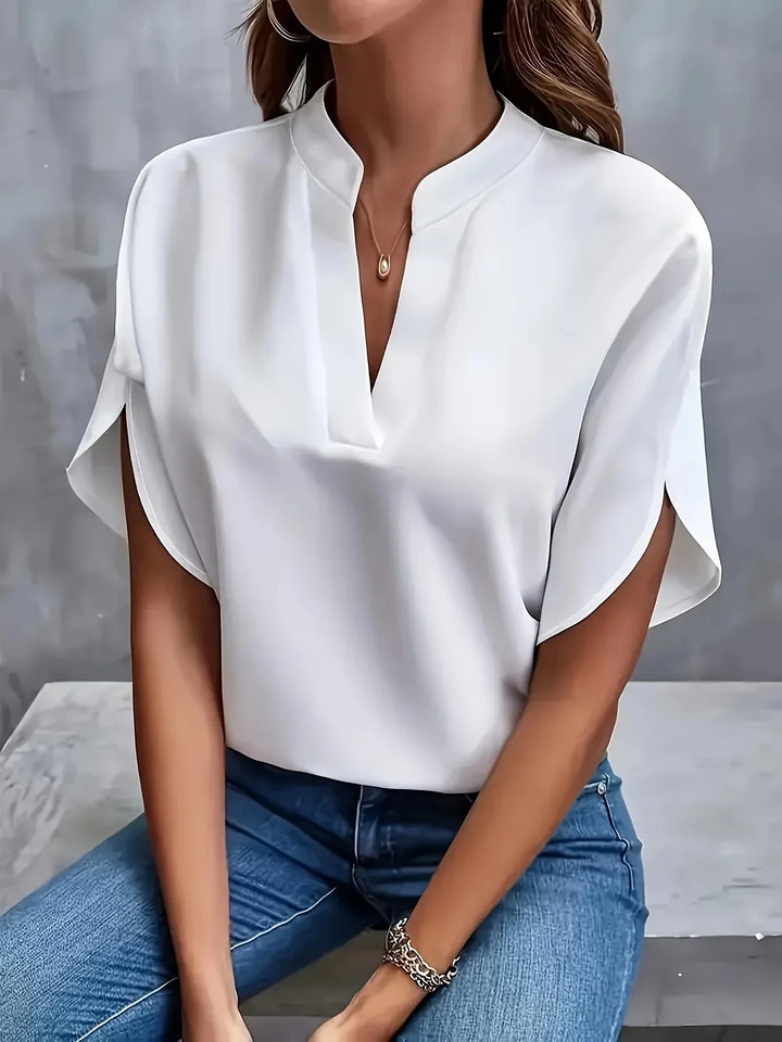 Female model showcasing a refined V neck blouse with split sleeve detail on a clean background.