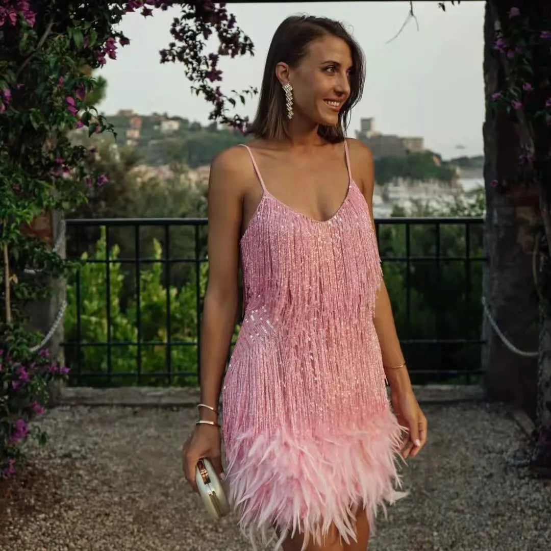 Woman wearing a pink fringe dress standing outdoors with greenery in the background