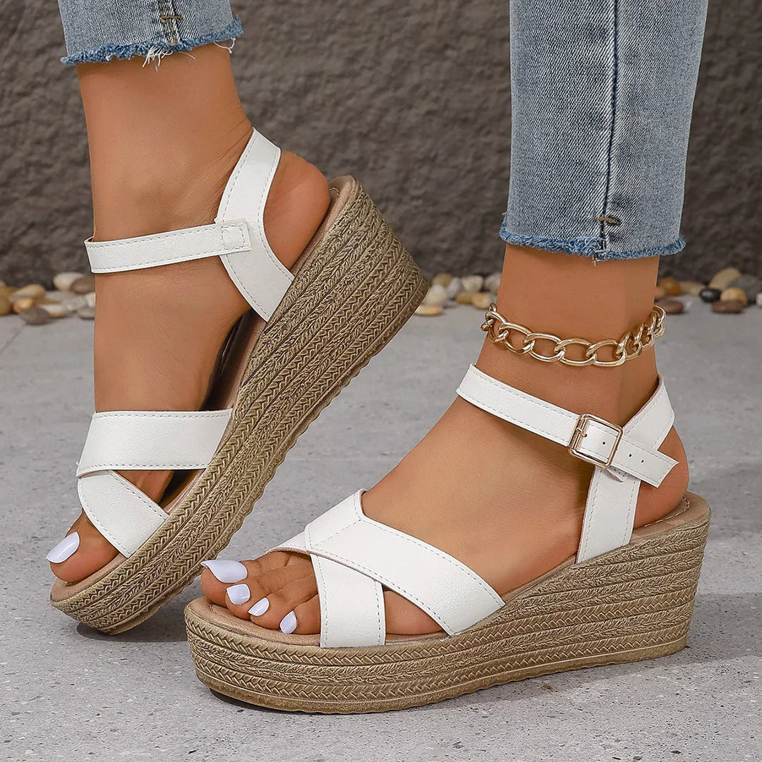 Close side view of straps on wedge sandals foot plain background