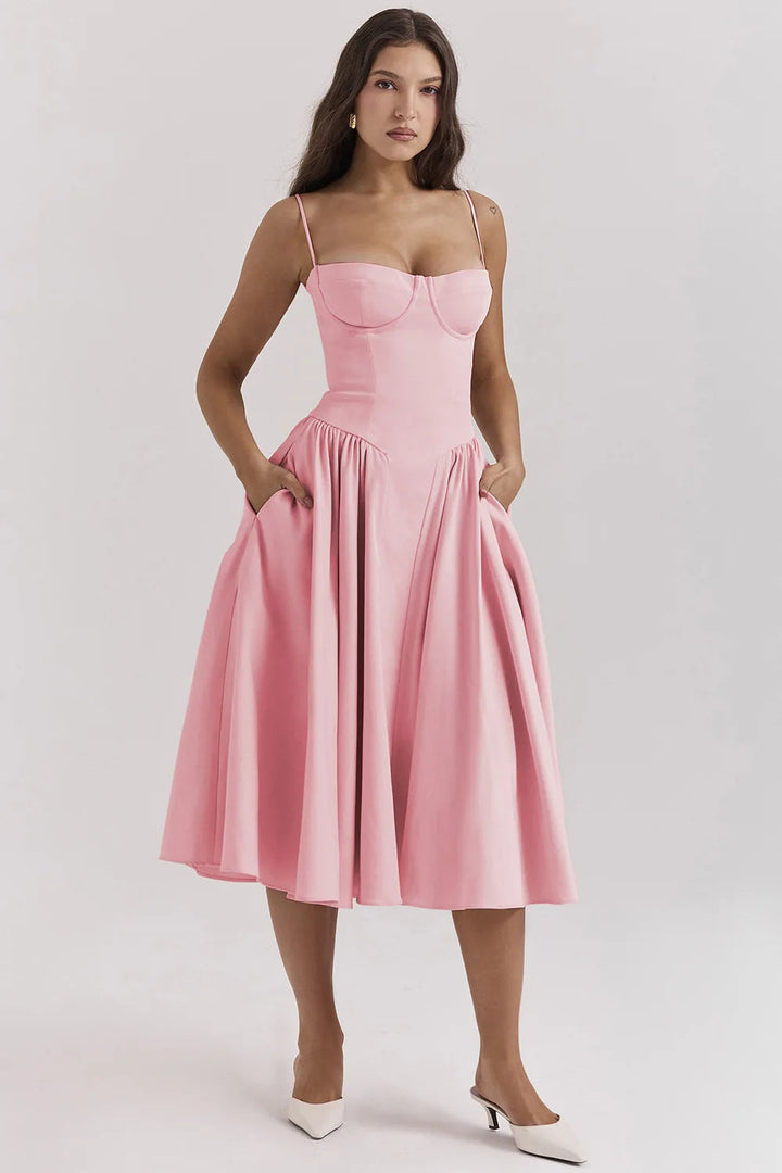 Woman in a delicate strap midi dress against a plain background