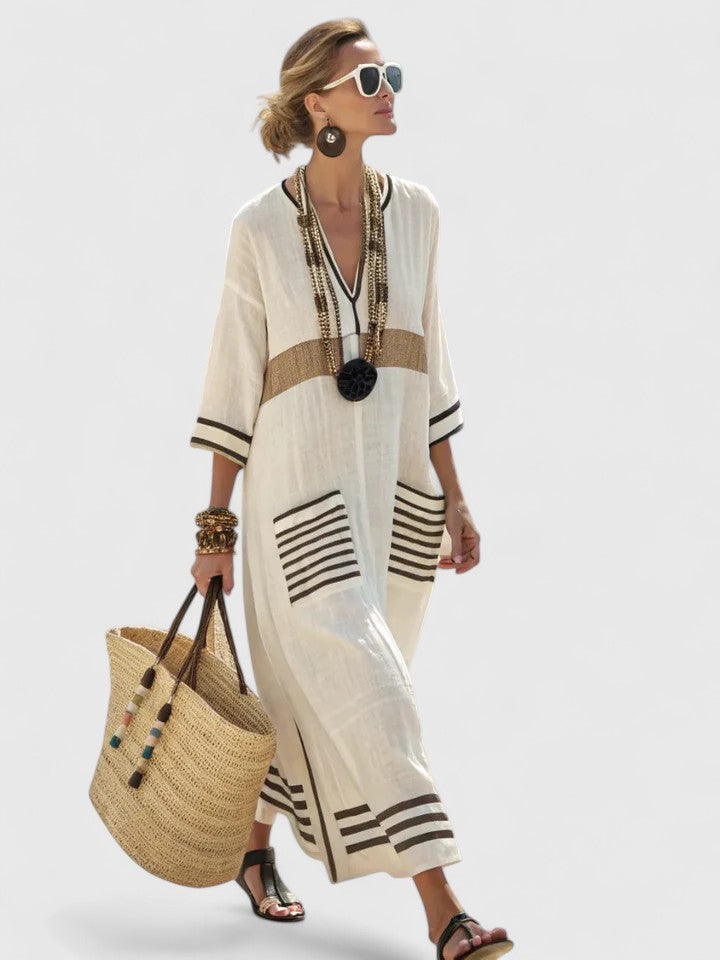 Model in a flowing striped maxi kaftan dress against a plain background.