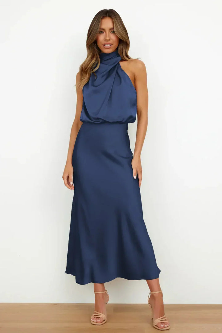Female wearing a glossy satin evening dress on a minimal background.
