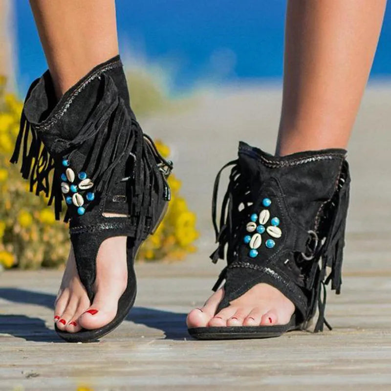 Angled front view foot wearing fringed sandals plain background