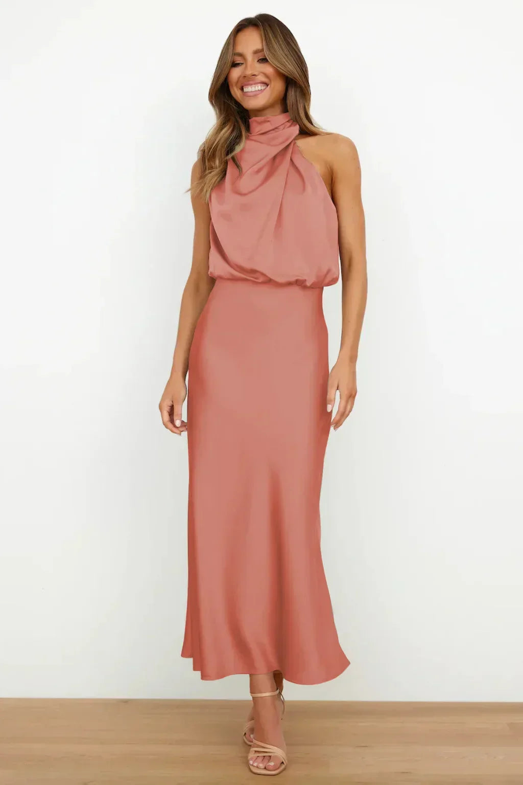 Woman standing in a satin halter dress designed for formal occasions.