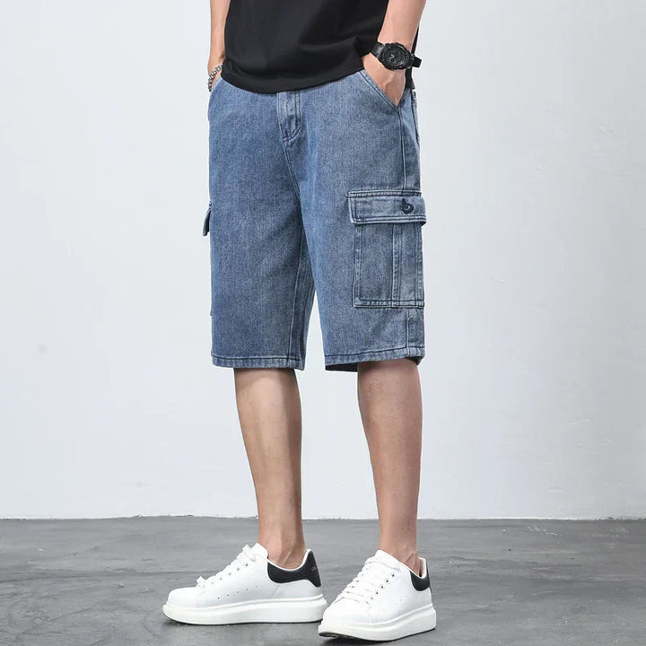 Model wearing casual blue cargo shorts with flap pocket on a plain background.