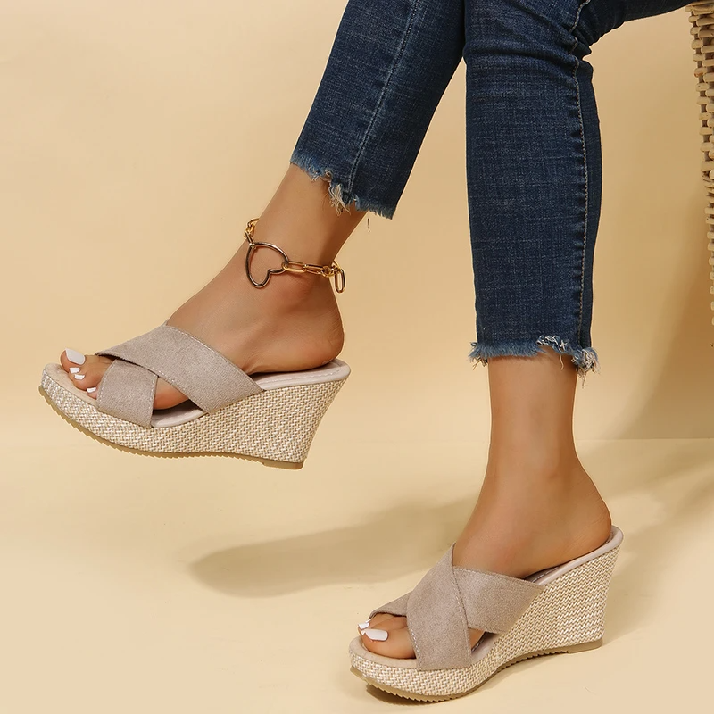 Woman standing in casual summer sandals against a plain background.