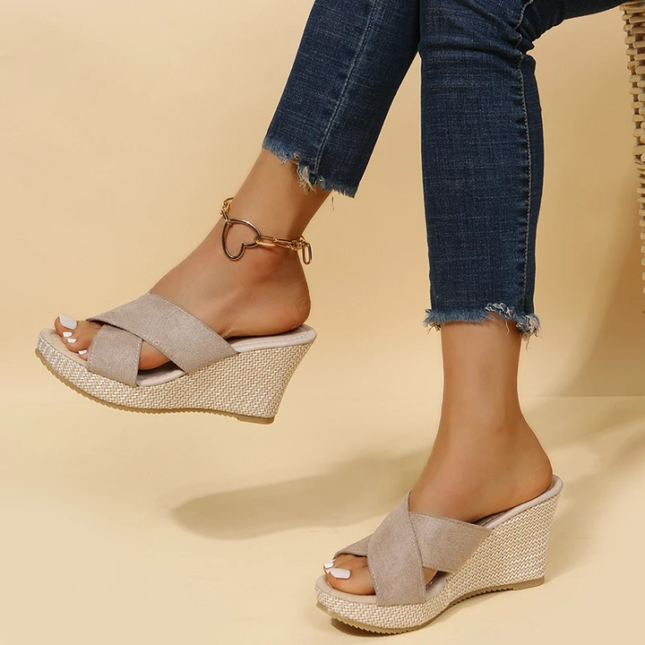 Woman standing in casual summer sandals against a plain background.