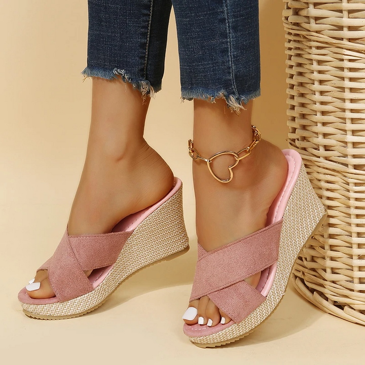 Woman wearing easy slip on sandals on a plain background.