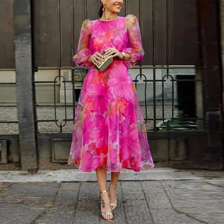 Female model wearing a floral midi dress with long sleeves against a plain background.
