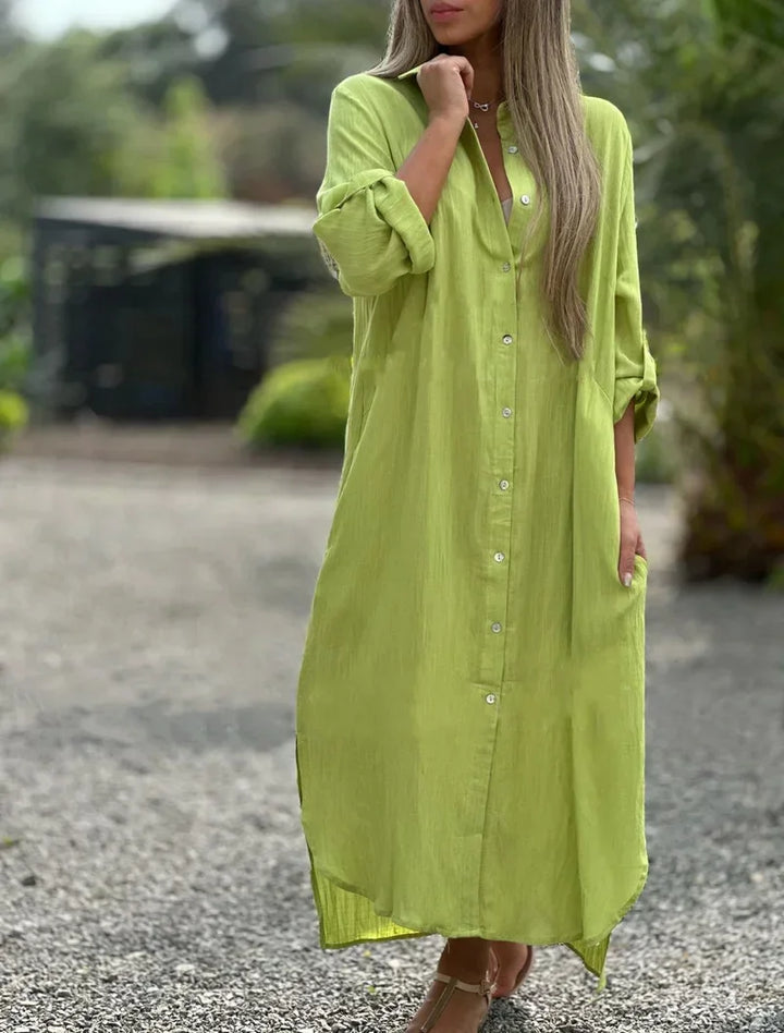 Woman wearing a loose oversized maxi dress with button-front detail on plain background.