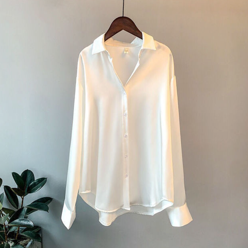 Model styled in a classic long sleeve button down blouse with a plain background.