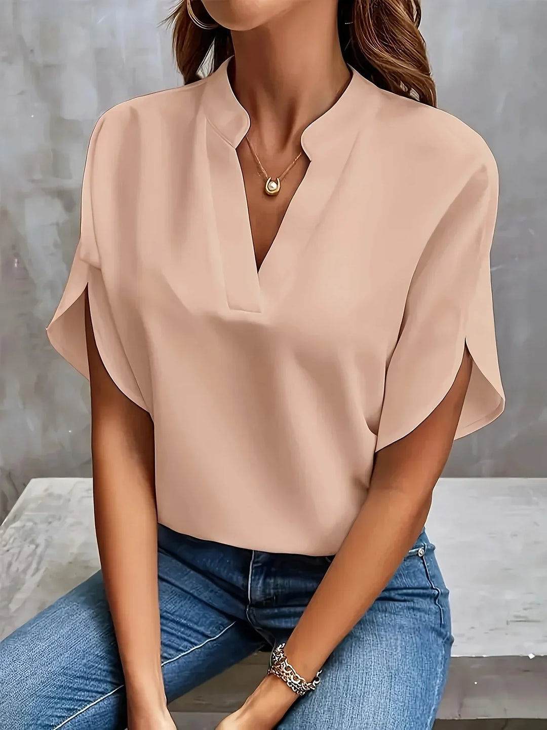 Model in a refined V neck top with soft silhouette on a plain background.