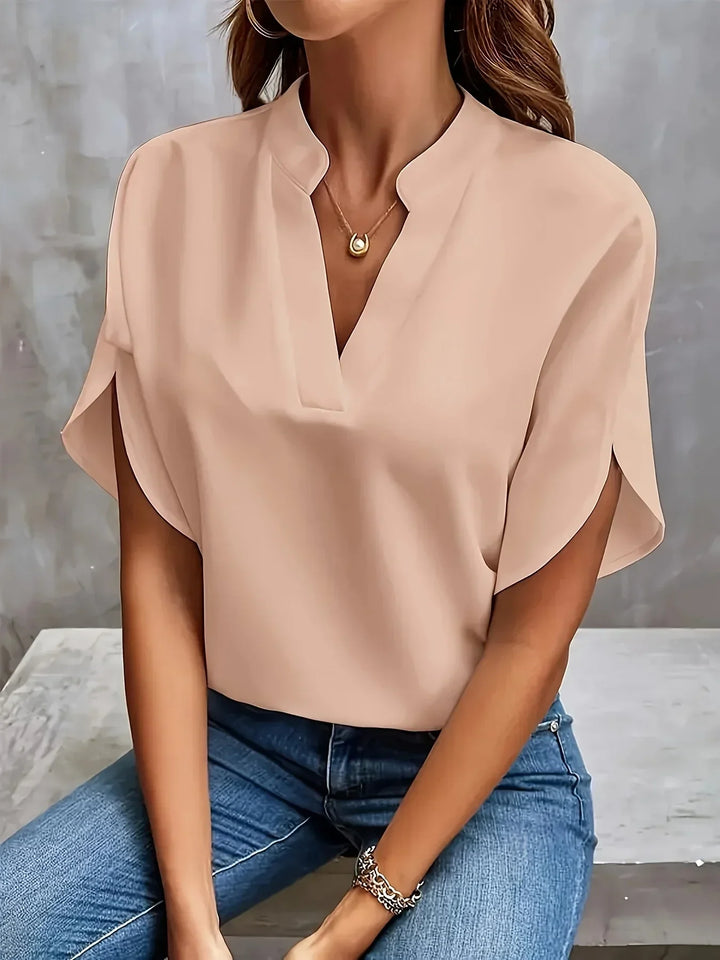 Model in a refined V neck top with soft silhouette on a plain background.