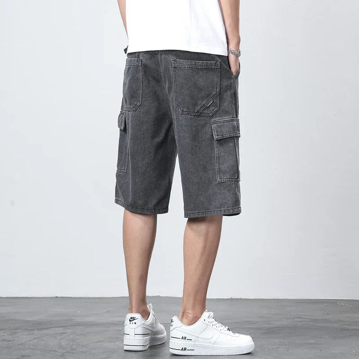  Model wearing blue cargo shorts with belt loops and flap pocket on a plain background.
