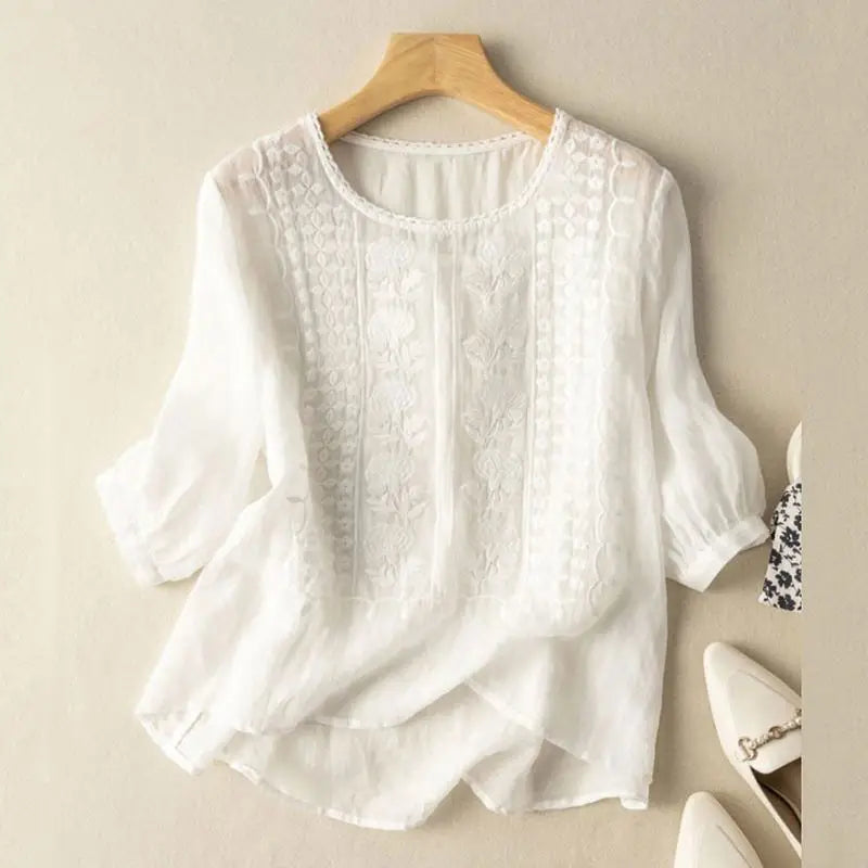 Embroidered round neck blouse on a model against a plain background.