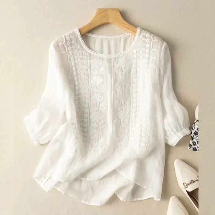 Embroidered round neck blouse on a model against a plain background.